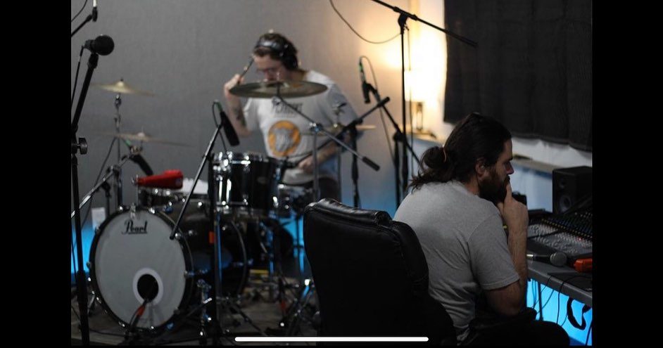 Drummer recording while engineer works at the console